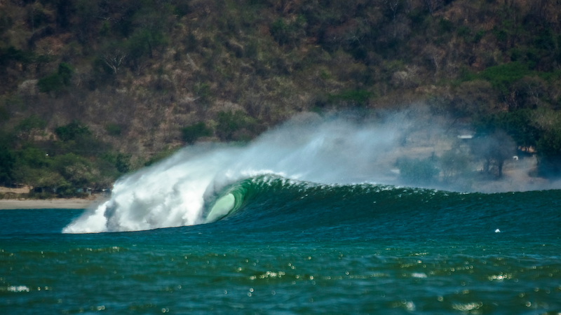 wave breaking under brown cliffs
